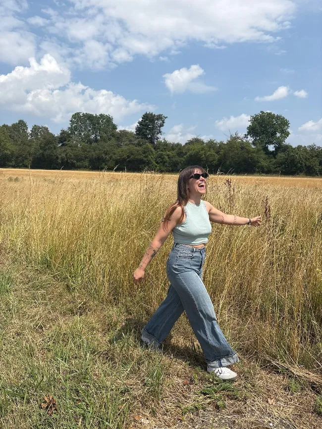 Sarah Bove geht lachend über ein sommerliches Feld