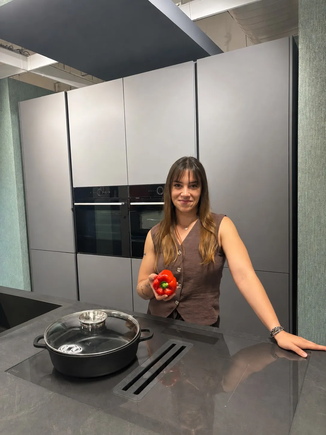 Sarah Bove steht in ihrer Küche und hält eine Tomate in der Hand
